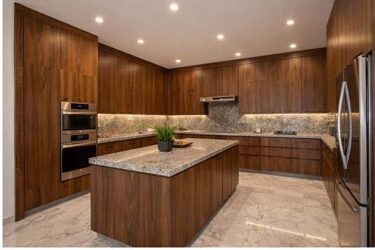 Cocina cerrada con cubierta de granito natural, gabinetes de madera sólida, iluminación empotrada y diseño funcional con excelente distribución.